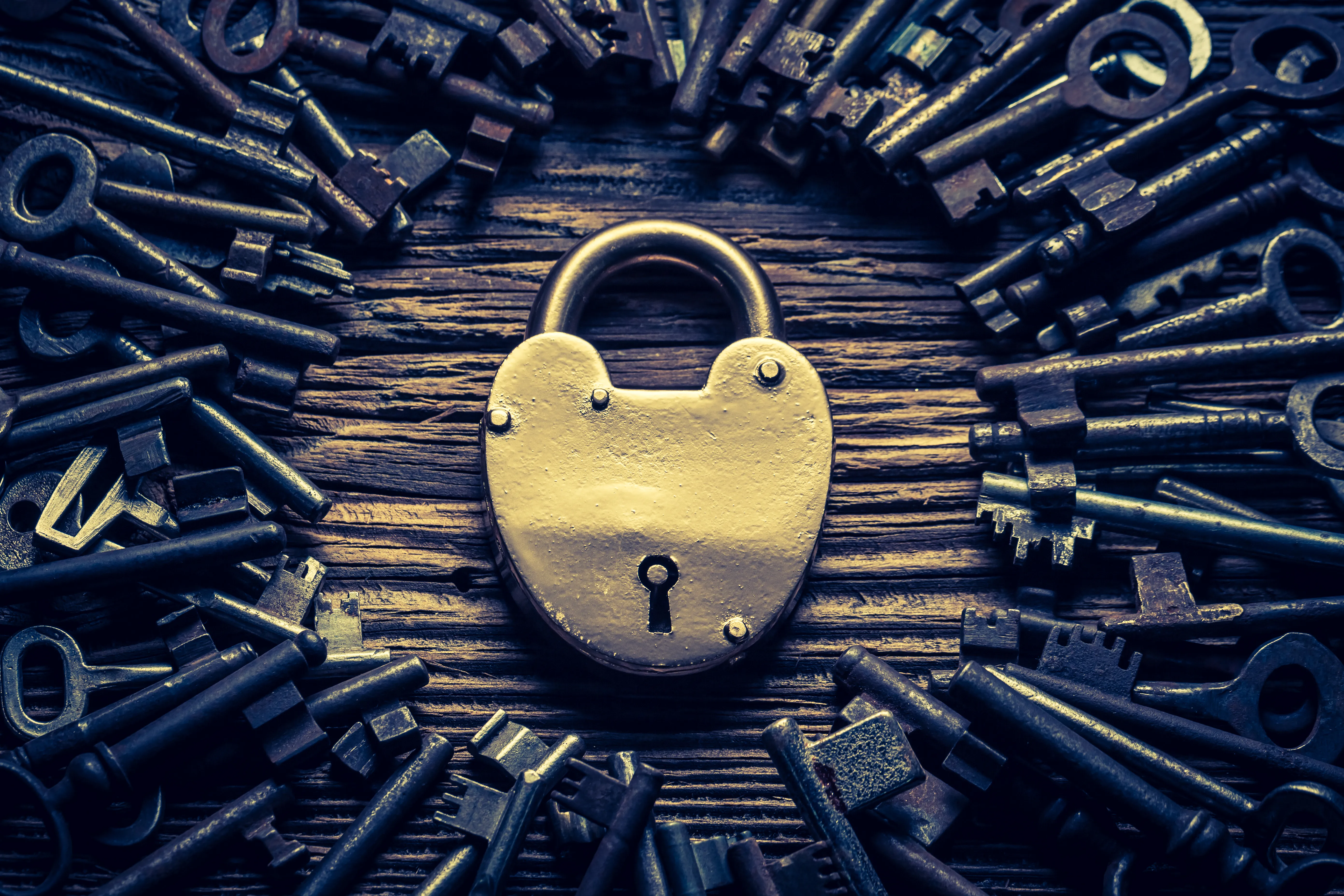 Antique padlock surrounded by scattered keys, symbolizing cloud misconfigurations and how TRaViS ASM secures open access points from cyber threats.