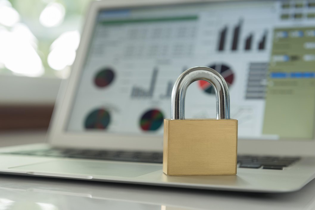 Gold padlock on laptop with data charts in background, symbolizing TRaViS EASM detecting shadow IT and rogue digital assets in attack surface management.