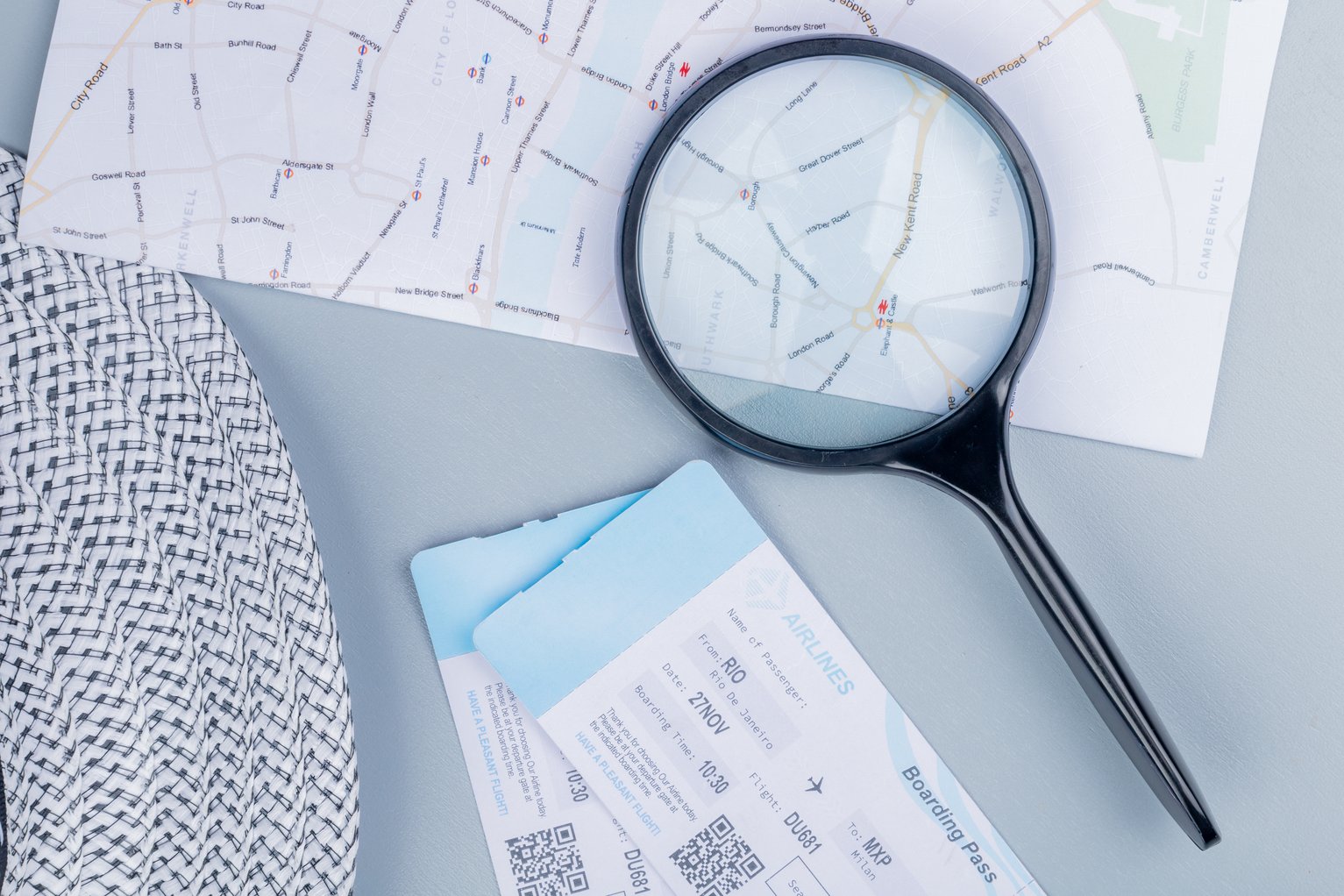 Magnifying glass over map and boarding pass representing TRaViS EASM using real-world data to improve cybersecurity risk assessments and attack surface analysis.