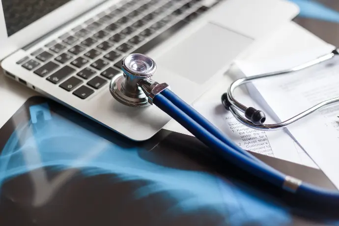 Laptop with a stethscope, and xrays on a white table.