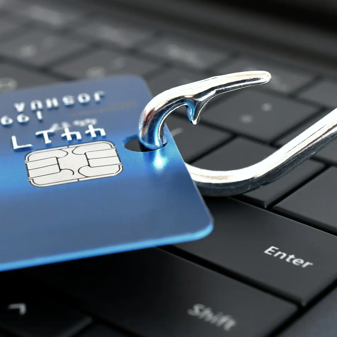 Image of a credit card with a hook through it on top of a keyboard.