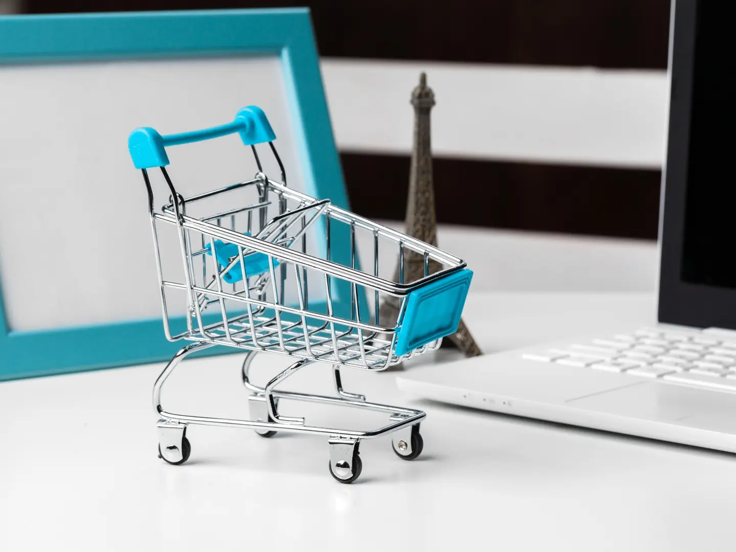 Image of a shopping cart, laptop, and a statue on a desk.