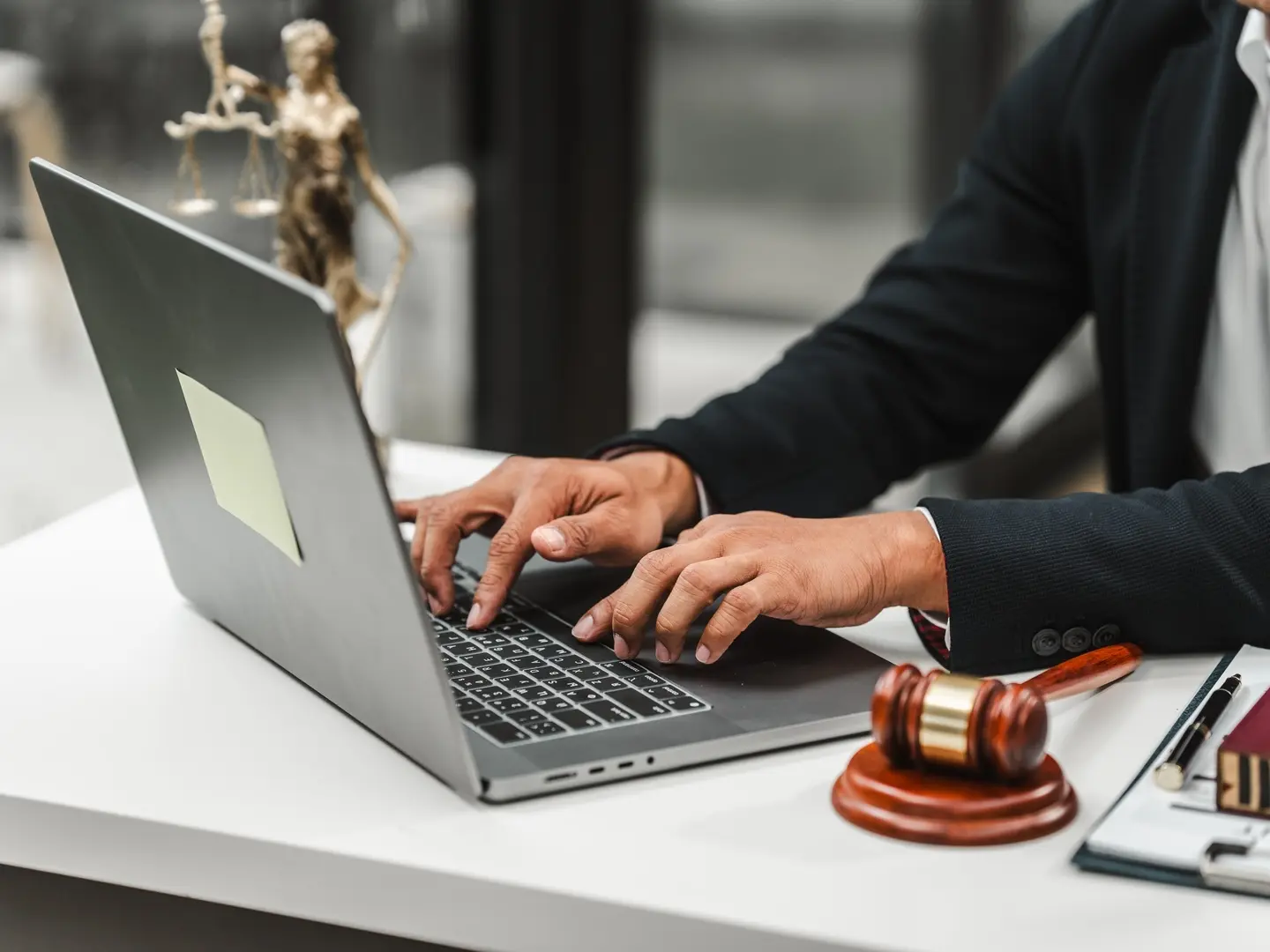 Person in the legal industry using a laptop. Gavel is next to laptop.